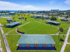 Un gran complex esportiu amb diverses pistes, un edifici central amb teulada verda i edificis residencials al voltant.