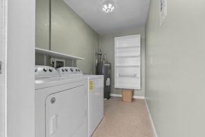 A laundry room with a washer and dryer, a water heater, and a shelf with a basket. - 50 Steps to the Beach - 3/2 Island Retreat (Fort Pierce)