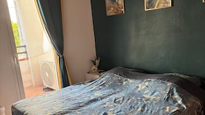 Una camera da letto con un letto, una ventola a soffitto, una finestra con tende e opere d'arte alle pareti.