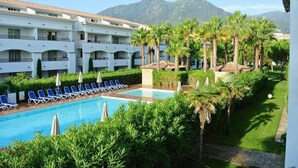 Un hotel con piscina, palme e montagne sullo sfondo.