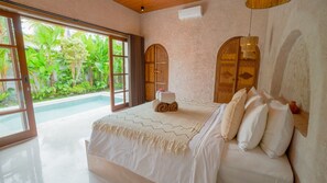 Quarto com cama grande, vista para uma piscina e um jardim tropical lá fora.