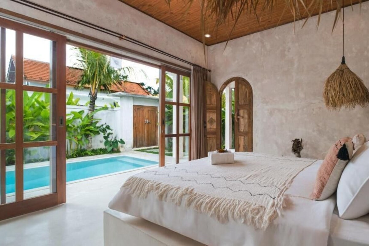 Quarto com cama grande, vista para uma piscina e teto rústico.