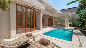 A poolside area with lounge chairs and a clear blue pool. - Nick Villas (Ubud)