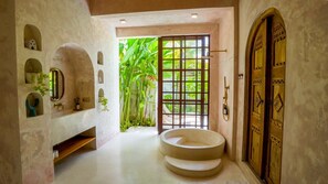 Un baño con bañera, ducha y puerta que da a un jardín.