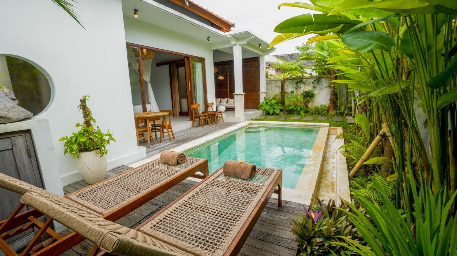 A poolside area with lounge chairs, a small table, and a covered seating area.