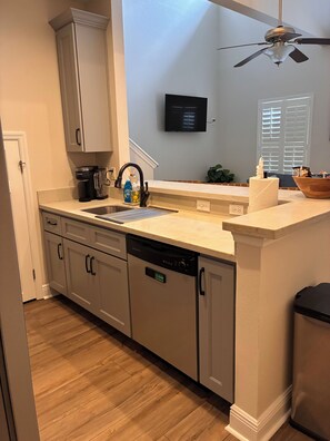 A kitchen with a dishwasher, a coffee maker, and a sink. - The Gator’s Den at Lionsgate (Gainesville)