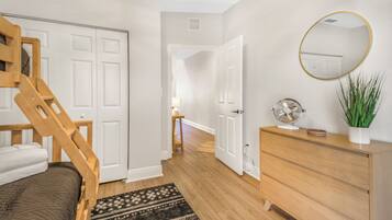 Une chambre à coucher avec un lit, une commode, un miroir et un escalier.