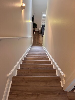 A wooden staircase with white trim leading to a landing. - The Gator’s Den at Lionsgate (Gainesville)