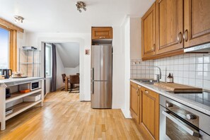 A modern kitchen with wooden cabinets, a stainless steel refrigerator, and a dining area with a table and chairs. - Tromsø apartment - panoramic views and terrace. (Troms)