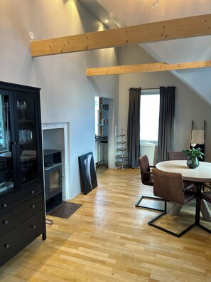 Un intérieur moderne comprenant un coin repas, un meuble noir et un escalier menant à un niveau supérieur.