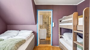 Ein Schlafzimmer mit einem Etagenbett, einem Einzelbett und einer Tür zu einem Badezimmer.