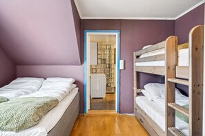Une chambre avec un lit superposé, un lit simple et une porte donnant sur une salle de bain.