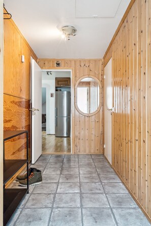 A hallway with wooden paneling, a stainless steel refrigerator, and a tiled floor. - Tromsø apartment - panoramic views and terrace. (Troms)