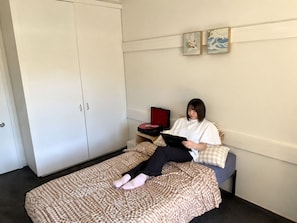Ein Zimmer mit einem Bett, einem Kleiderschrank und einem roten Koffer.