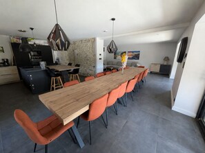 Une cuisine moderne avec un coin repas, comprenant une longue table en bois et des chaises orange.