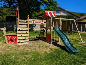 Un parque infantil de madera con un tobogán y estructuras para escalar.