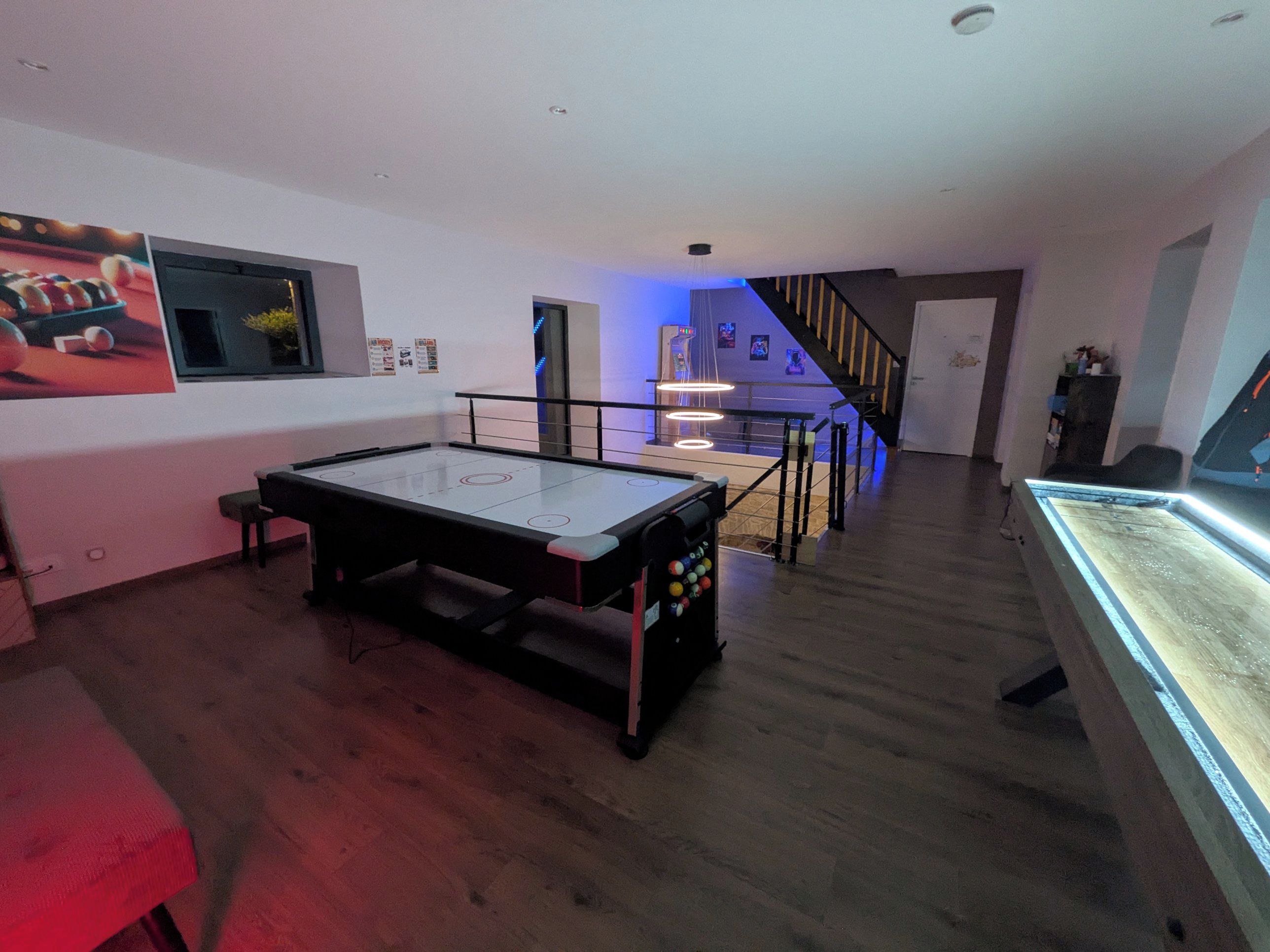 Una habitación con mesa de billar, una escalera y una vitrina.