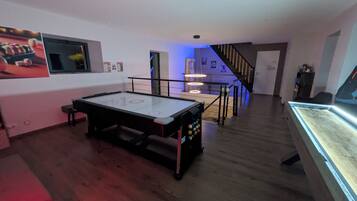 Una habitación con mesa de billar, una escalera y una vitrina.