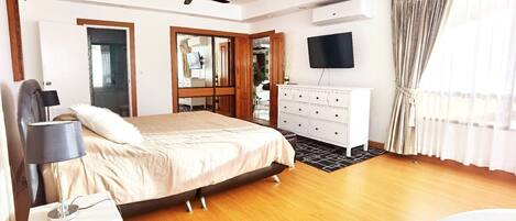 Un dormitorio con cama, cómoda, televisor y ventilador de techo.