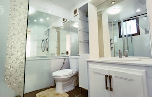 Een moderne badkamer met toilet, douche, spiegel en wastafel.