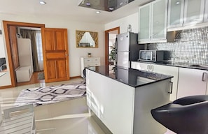 A modern kitchen with a central island, white cabinetry, and a black countertop. - Jomtien beach center point, direct sea-view, THE best location! (Muang Pattaya)