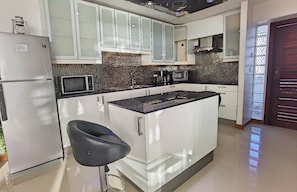 Eine moderne Küche mit weißen Schränken, einer schwarzen Arbeitsplatte und einem Edelstahl-Kühlschrank.