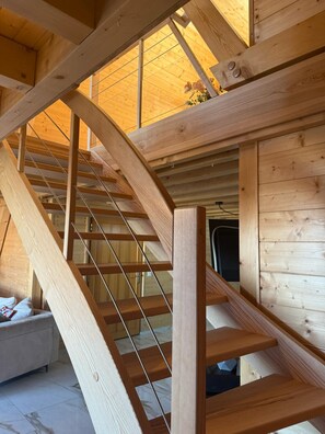 A wooden staircase with a glass balustrade leading to an upper level.