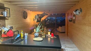 Une cuisine moderne avec un îlot central, des murs en bois et une vue sur l’extérieur.