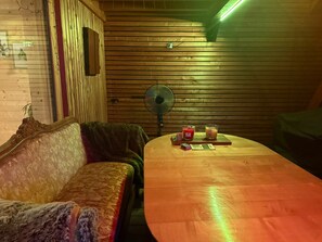 Una habitación con una pared de listones de madera, un sofá, una mesa con velas y un ventilador.