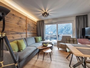 Ein modernes Wohnzimmer mit einer Holzwand, einem grauen Sofa, einem kleinen runden Tisch und einem Fernseher.
