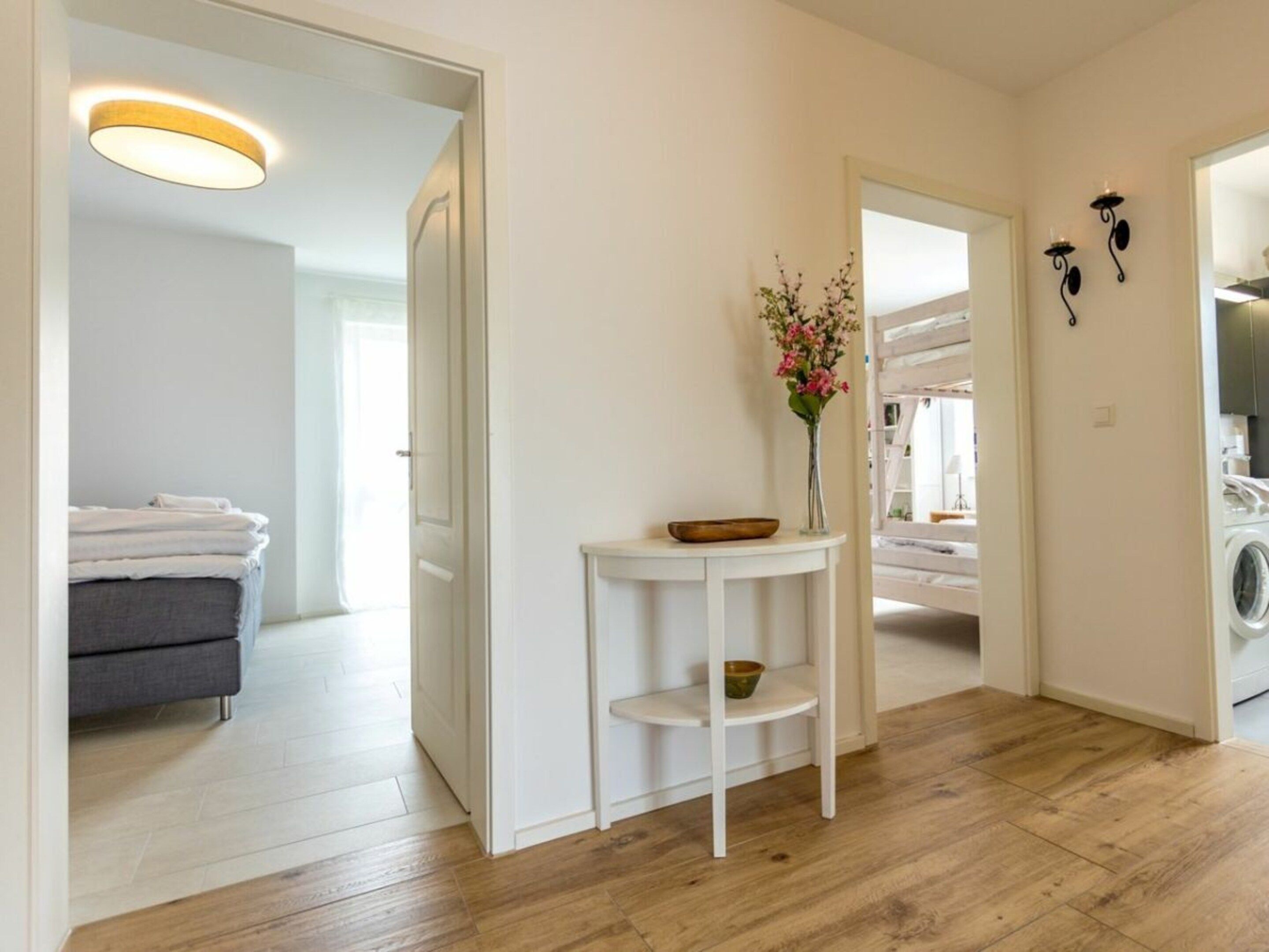 A clean, modern bathroom with a white sink, a mirror, and a vase with flowers.