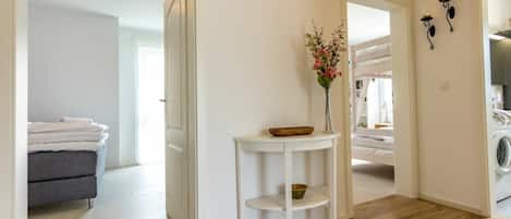 A clean, modern bathroom with a white sink, a mirror, and a vase with flowers.