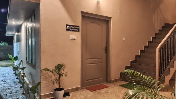 Una escalera que conduce a una puerta con la leyenda 'A1 Cheruthodath Apartments'.