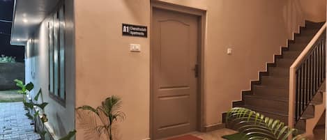 Escadaria que leva a uma porta com a inscrição 'A1 Cheruthodath Apartments'.