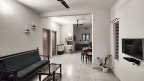 Una sala de estar con sofá, mesa de centro y televisión. Hay una zona de cocina con mesa y sillas.