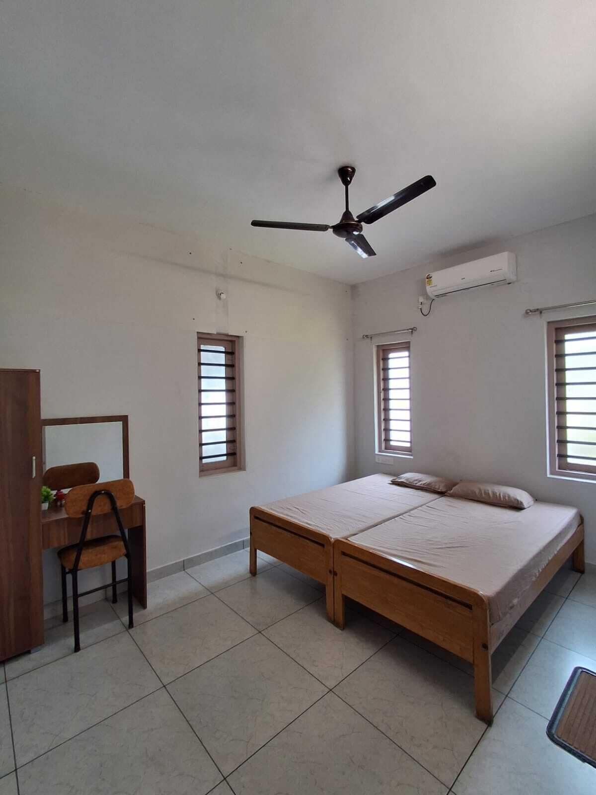 A bedroom with a bed, a desk, a chair, and a ceiling fan.