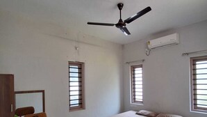 A bedroom with a bed, a desk, a chair, and a ceiling fan.
