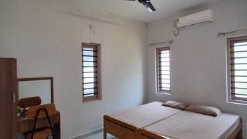 A bedroom with a bed, a desk, a chair, and a ceiling fan.