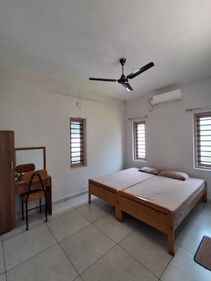 A bedroom with a bed, a desk, a chair, and a ceiling fan.