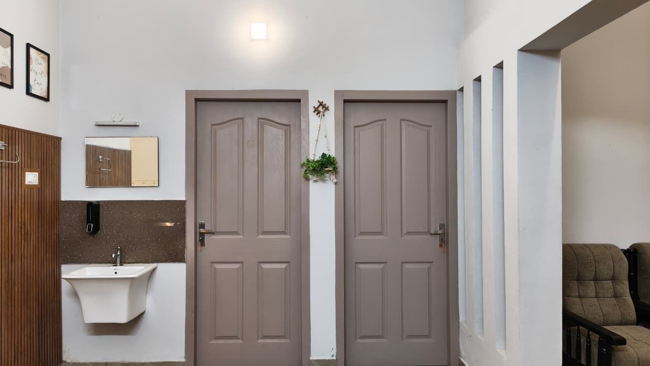 A hallway with two doors, a sink, and a chair.