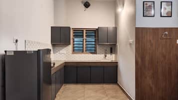 Una cocina compacta con armarios oscuros, una ventana con persianas y un panel de madera en la pared derecha.