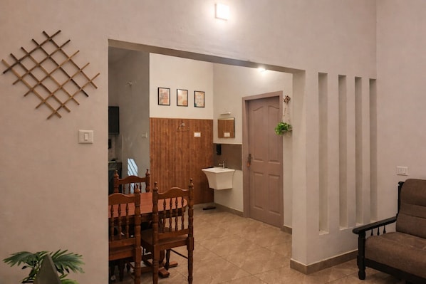 A dining area with a wooden table and chairs, a kitchen with a sink, and a door leading to another room.