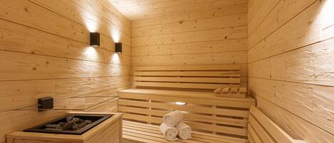 A sauna with wooden benches and a bench with towels.