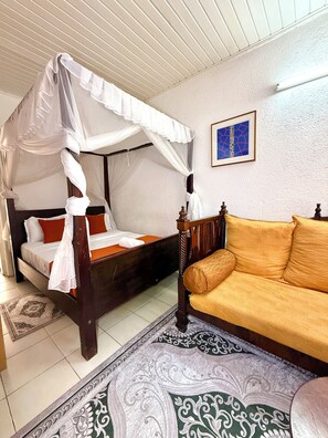 A bedroom with a four-poster bed, a sofa, and a patterned rug.