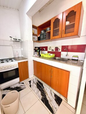 A compact kitchen with wooden cabinets, a gas stove, a microwave, and a sink.