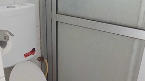 Een kleine, compacte badkamer met een wit toilet, een zichtbare toiletrolhouder en een glazen douchewand.