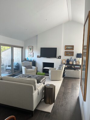 A modern living room with a flat-screen TV, sofas, a coffee table, and a fireplace.