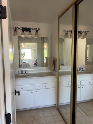 A bathroom with a double sink vanity, a large mirror, and a ceiling light fixture. - Beautifully remodeled and furnished Spacious 3 condo in Oaks North 55+ Community (San Diego)