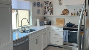 Eine moderne Küche mit weißen Schränken, einem Einbauofen, einem Kühlschrank und einem Fenster mit Blick.
