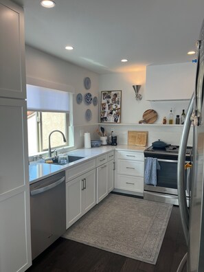 A modern kitchen with white cabinetry, a built-in oven, a refrigerator, and a window with a view. - Beautifully remodeled and furnished Spacious 3 condo in Oaks North 55+ Community (San Diego)